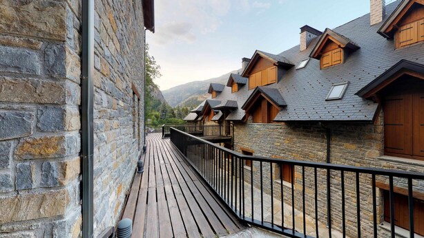 Une rangée de bâtiments en pierre, dotés de balcons en bois et d’une terrasse en bois.