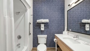 Une salle de bain moderne avec des toilettes blanches, une douche, un lavabo et un miroir.