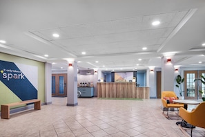 A hotel lobby with a reception desk, seating area, and a wall with a motivational quote. - Spark by Hilton Dumas (Dumas)