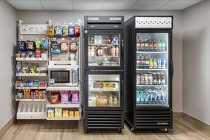 Three vending machines stocked with snacks, beverages, and microwaves.