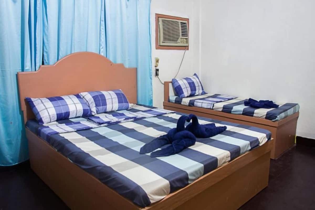 Una habitación con dos camas, cada una con una colcha a cuadros y almohadas.