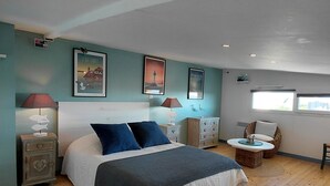 Een slaapkamer met een bed, twee nachtkastjes, een rieten stoel en een raam.