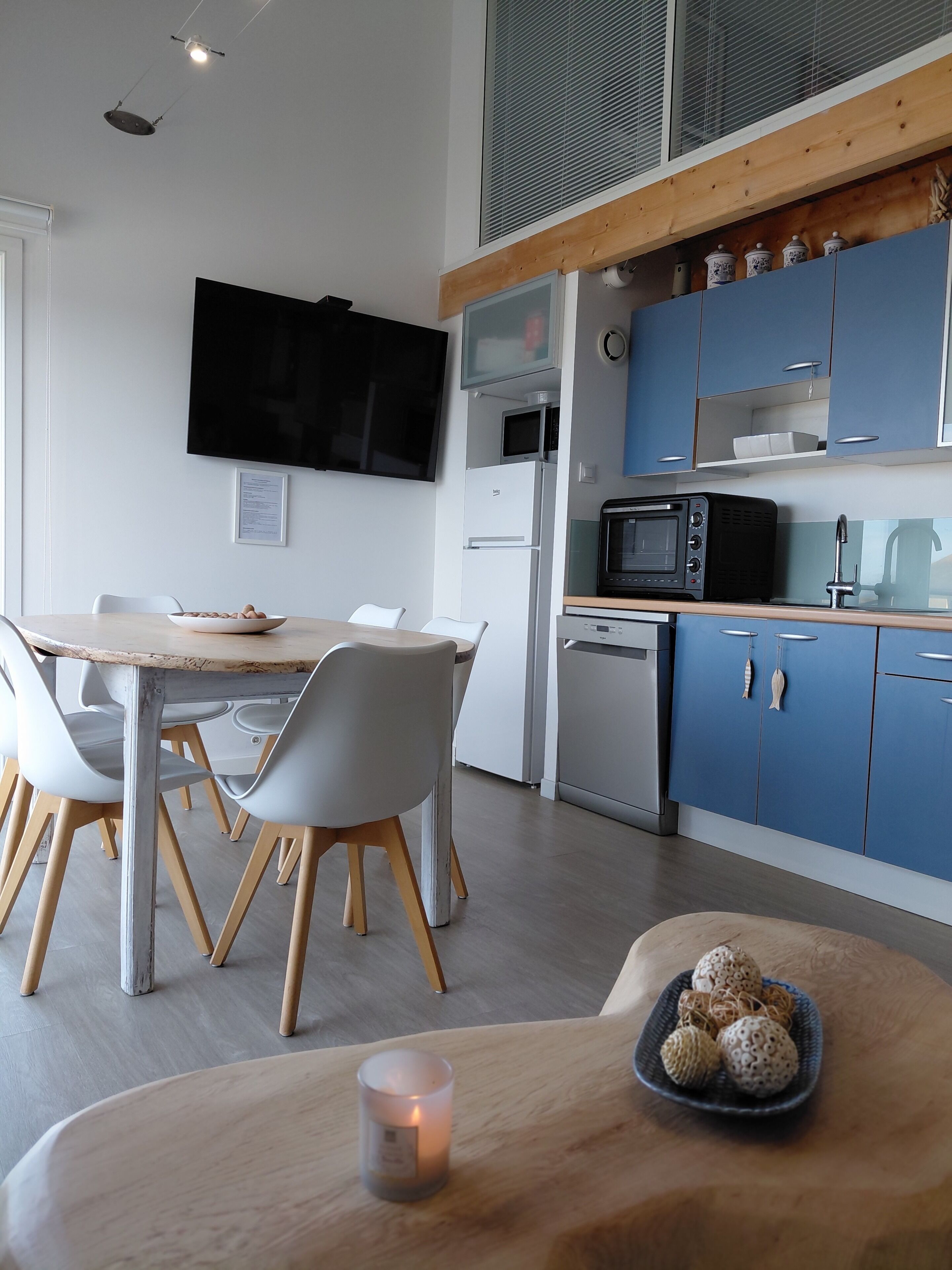 Una cocina moderna con armarios azules, un microondas, un horno tostador y un televisor de pantalla plana montado en la pared.