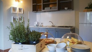 Una cocina con estufa, fregadero y refrigerador. Hay platos y una planta en la encimera.