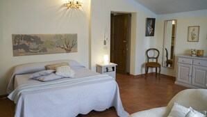 A bedroom with a bed, bedside table, chair, and a dresser. - Elegant apartment with pool view near the Spa (Sassetta)