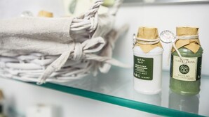 A glass shelf with a woven bag and two bottles of hair conditioner. - Elegant apartment with pool view near the Spa (Sassetta)