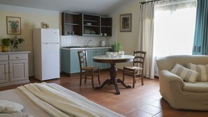 A compact living space with a kitchen, dining area, and a sofa. - Elegant apartment with pool view near the Spa (Sassetta)