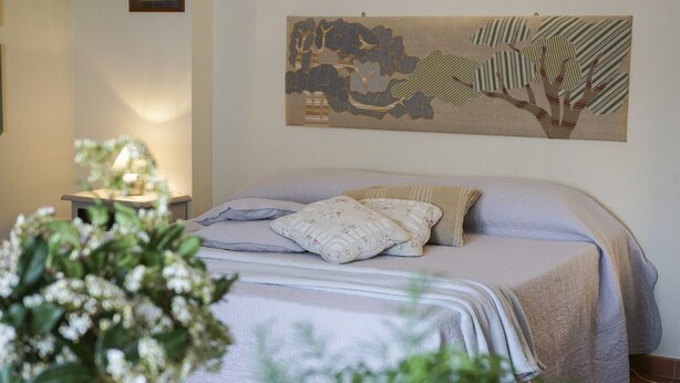 A bedroom with a bed, a nightstand, a lamp, and a wall art piece. - Elegant apartment with pool view near the Spa (Sassetta)