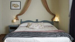 Ein Bett mit Baldachin, zwei Nachttischlampen, ein gerahmtes Bild an der Wand und ein Nachttisch.
