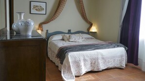 Ein Schlafzimmer mit Bett, Nachttisch, Kommode, einer Vase und einem Bild an der Wand.