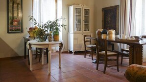 A dining area with a white table, chairs, a cabinet, and a painting on the wall.