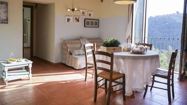 Un coin repas accueillant avec une table ronde, des chaises et une vue sur un paysage montagneux, visible à travers une grande fenêtre.