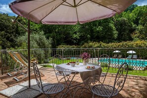 Une terrasse avec une table et des chaises, une piscine et une clôture.