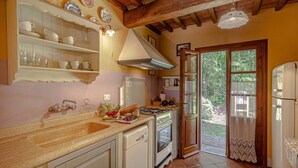 Eine Küche mit Holzbalkendecke, Spüle, Herd und Fenster zum Garten.