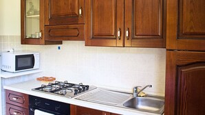 Une cuisine avec des meubles de rangement en bois, un four à micro-ondes, une cuisinière et un évier.
