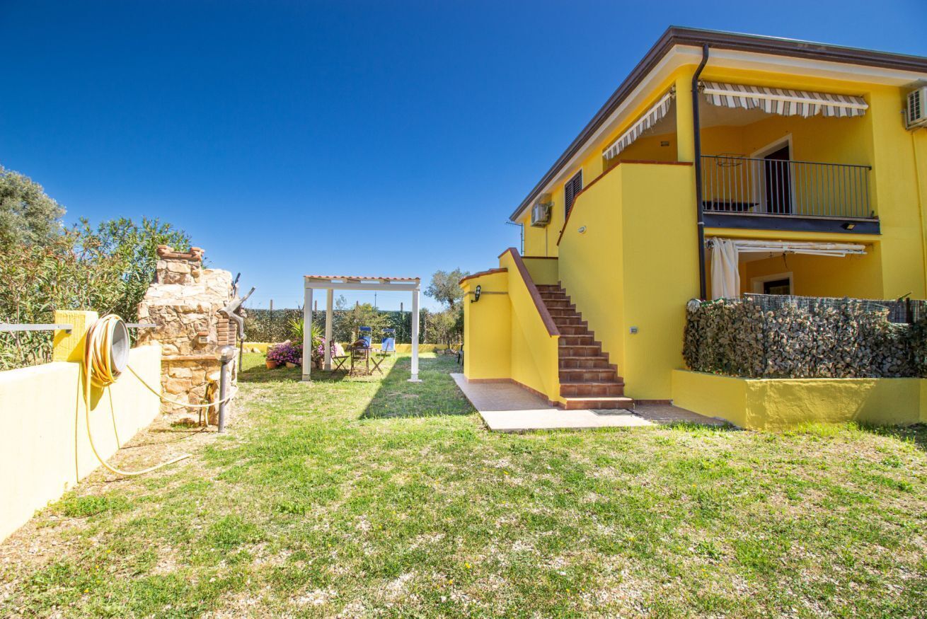 A yellow building with a covered patio and a stone wall.