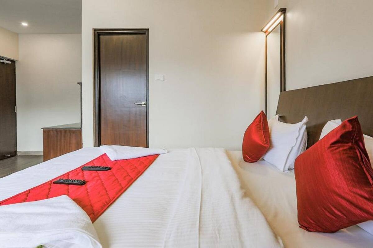 A hotel room with a bed, a bedside table, a mirror, and a door.