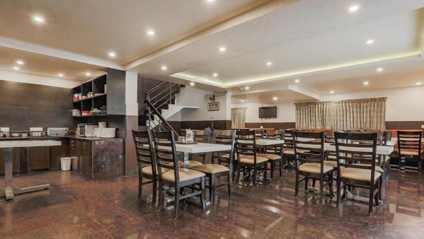 Un espaiós restaurant amb sostres alts, una escala central i diferents opcions de seients, incloent taules i cadires.