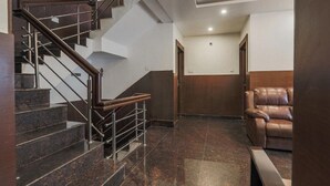 Un interior modern amb una escalinata de marbre, un sofà de pell i una porta de fusta.