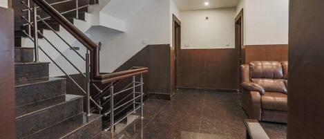 A modern interior with a marble staircase, a leather sofa, and a wooden door.