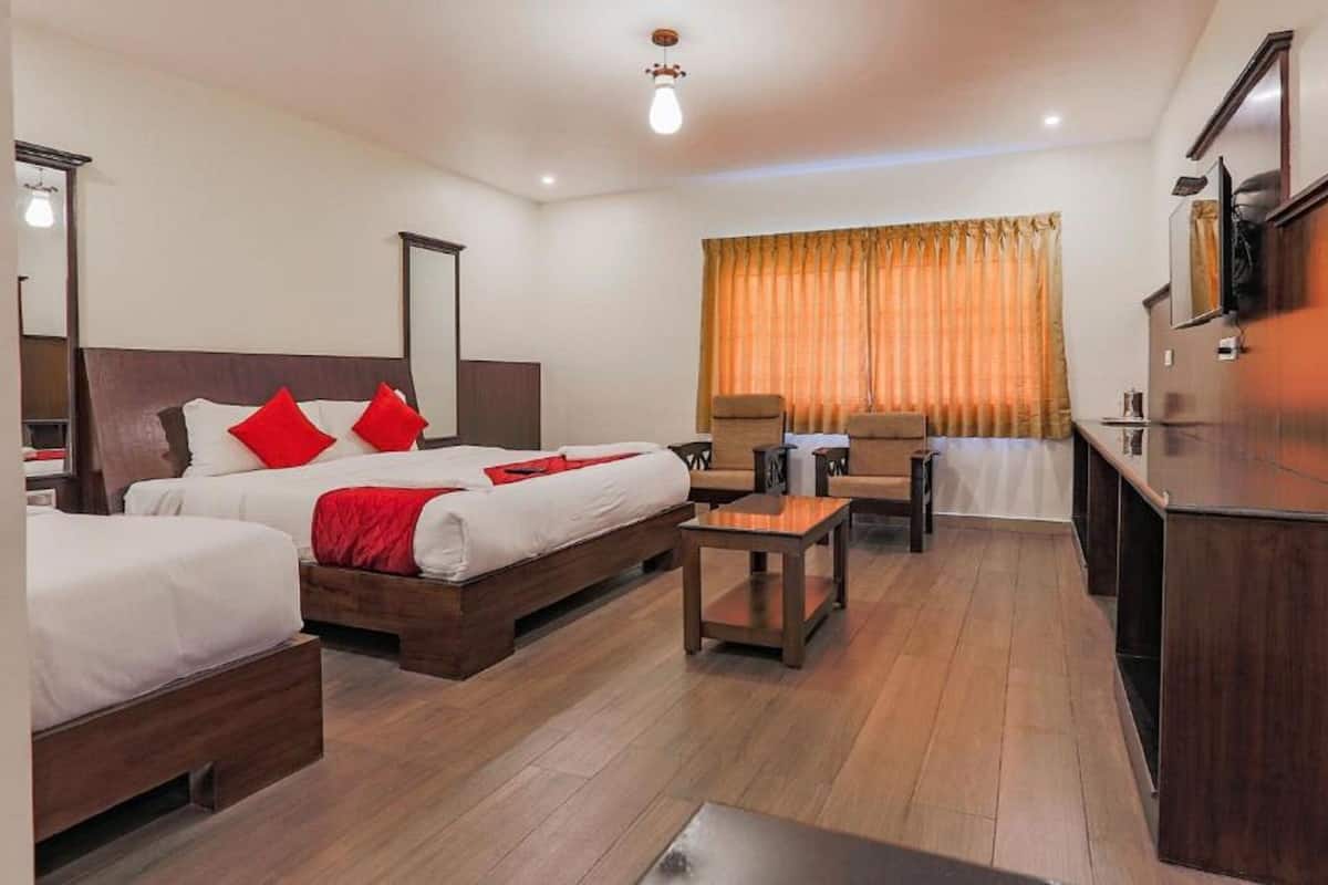 A hotel room with two beds, a desk, a chair, and a television.