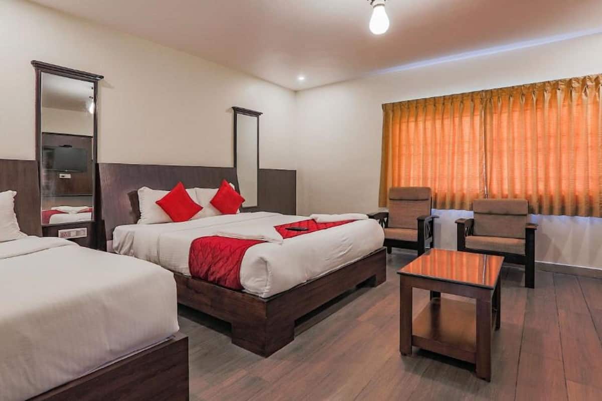 A hotel room with two beds, a chair, a small table, and a large mirror.