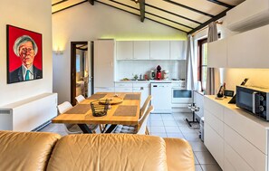 A modern kitchen with white cabinets, a dining area with a wooden table and chairs, and a living area with a sofa. - Amazing home in Bredene with WiFi (Bredene)