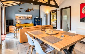 Un soggiorno moderno con un tavolo da pranzo in legno, un divano e una televisione.