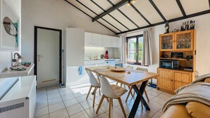Una cocina moderna con armarios blancos, una mesa de comedor con sillas y un mueble de madera con puertas de cristal.
