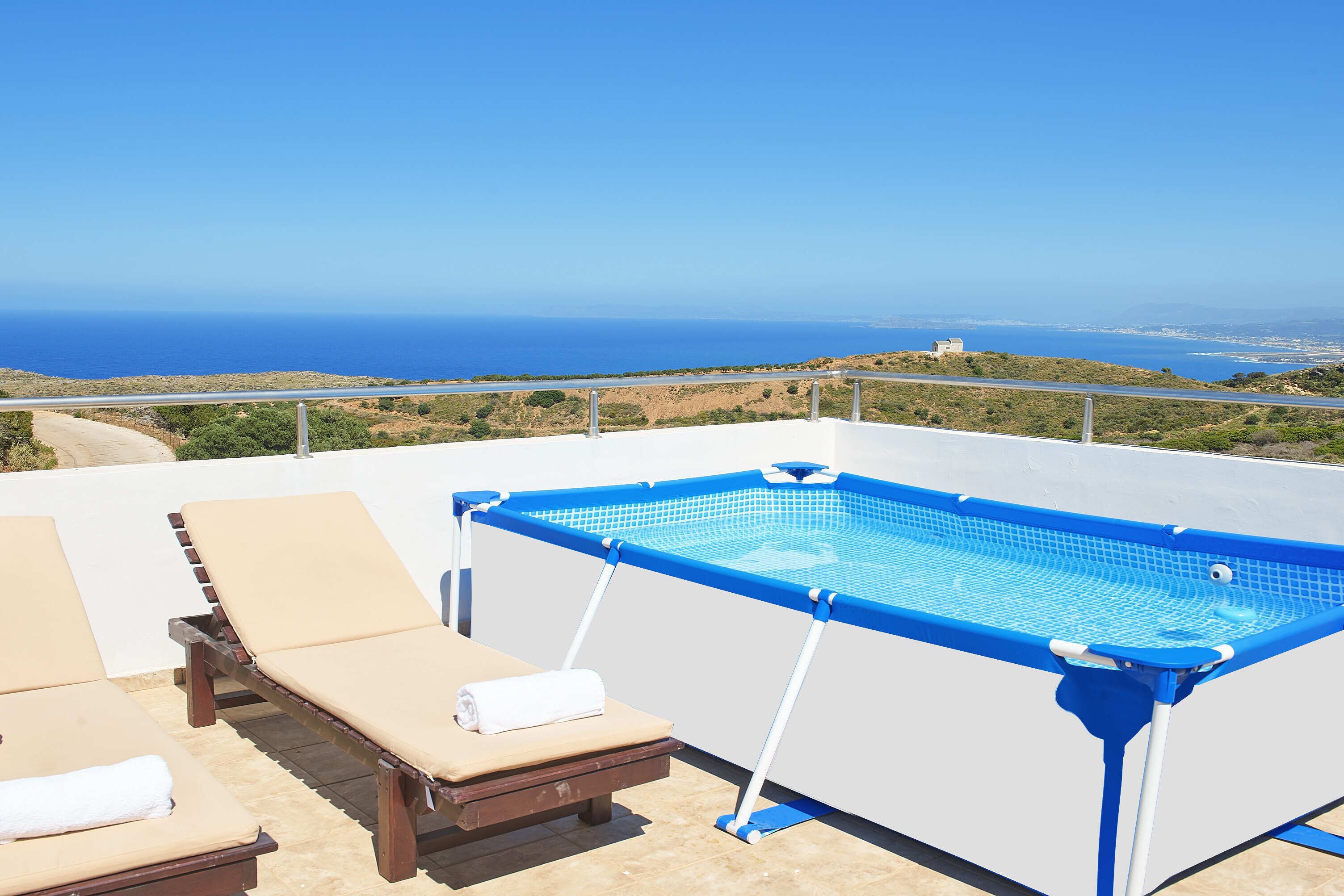 Una piscina al terrat amb gandules ia una vista del mar.