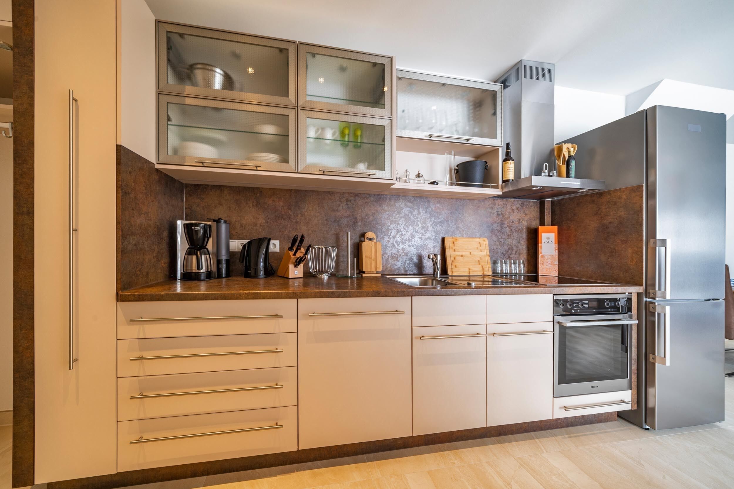 Una cocina moderna con horno empotrado, electrodomésticos de acero inoxidable y encimera de madera.
