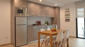 Eine moderne Küche mit integriertem Mikrowellenherd, einem Kühlschrank und einem Essbereich mit Holztisch und weißen Stühlen.