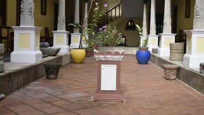 A courtyard with tiled flooring, stone columns, and potted plants. - Saradharam Heritage Hotel Lakshmi Vilas (Kattumannarkoil)