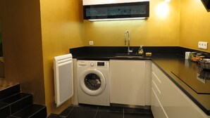 A compact kitchen with a washing machine, a sink, and a countertop with various items.