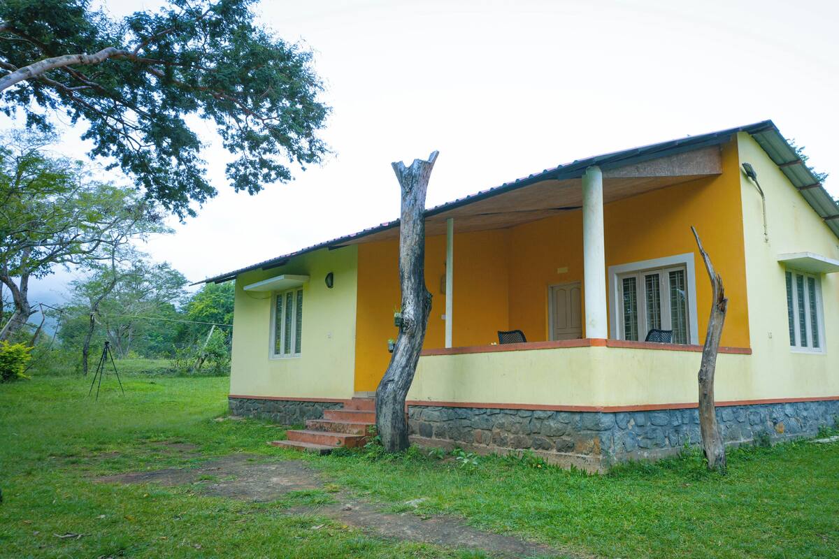 A single-story house with a porch, a stone foundation, and a grassy yard.