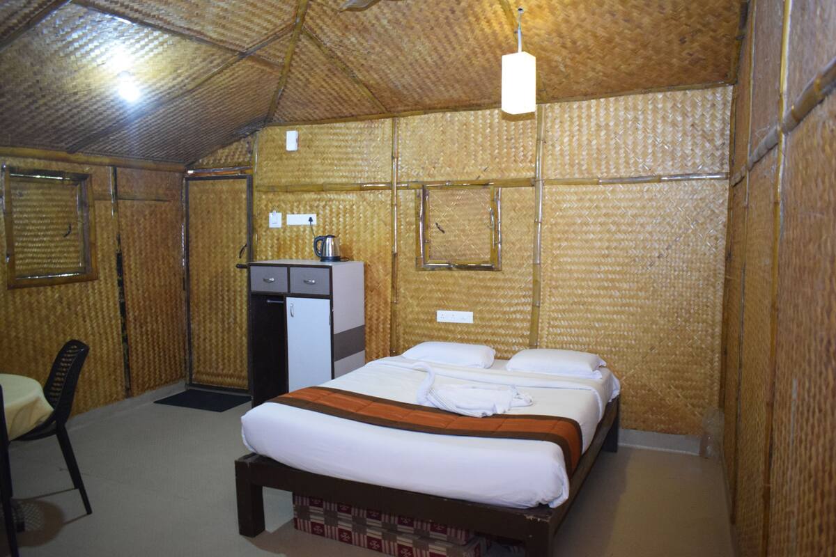 A room with a bed, a desk, a chair, and a small kitchenette.