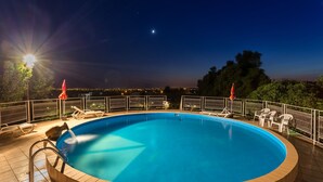 A circular pool with a wooden edge, surrounded by a white fence and white chairs. - Maisons de L'algarve Location C 3 (Estoi)