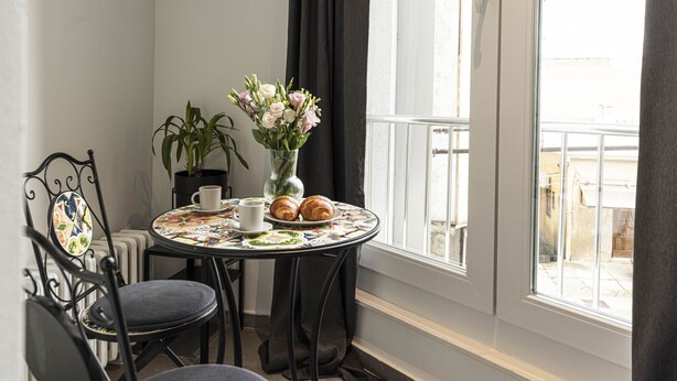 A corner room with a table set for two, a chair, a potted plant, and a window with a view. - Colors of Music (Zagreb)