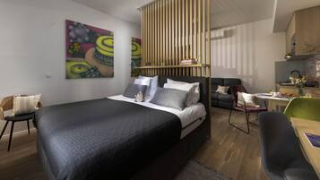 Ein modernes Schlafzimmer mit einem großen Bett, einer Couch, einer Essecke und einer Küche.