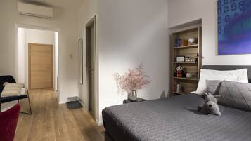 A bedroom with a bed, bedside table, lamp, and a bookshelf.