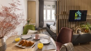 A modern living room with a dining area, a sofa, a TV, and a potted plant. - Colors of Music (Zagreb)