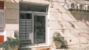 L'ingresso di un edificio con una porta in vetro, una cassetta delle lettere e condizionatori d'aria sulla parete.