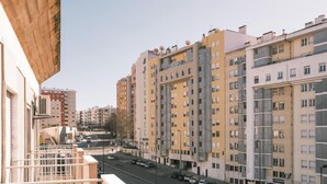 Un edificio residenziale a più piani con balconi, una strada di fronte e auto parcheggiate.