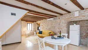 A kitchen with a stone wall, a white refrigerator, and a yellow sofa. - DeAmicis Studios by Irundo (Rovinj)
