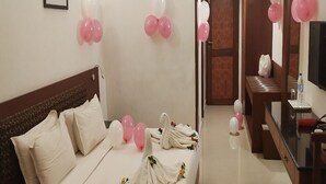 A hotel room with a neatly made bed, a wooden headboard, and a small table with a bottle and a glass. - French Avenue (Mahe)