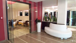 Un hall d’entrée moderne comprenant un espace d’accueil, un coin salon et une porte vitrée donnant accès à une salle à manger.