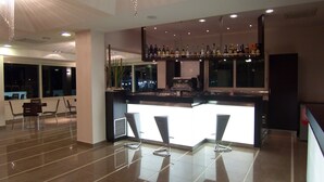 Un espace bar moderne avec un sol carrelé élégant, des tabourets de bar et une variété de bouteilles exposées sur des étagères.