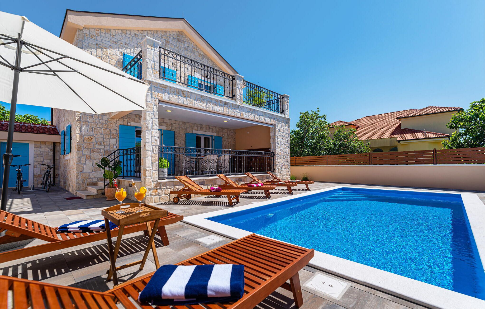 A stone building with a pool, outdoor seating, and a covered patio.