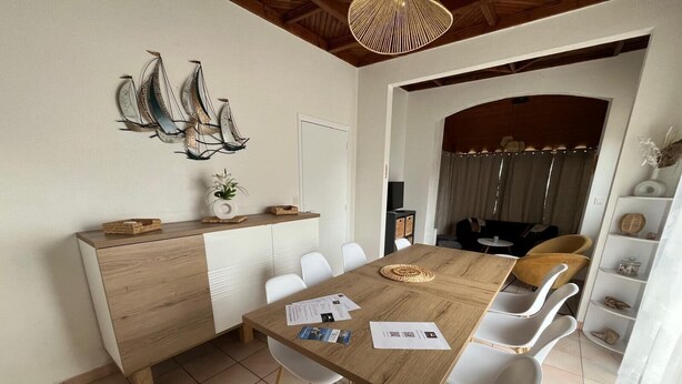 A dining area with a wooden table, white chairs, a decorative wall piece, and a ceiling light fixture.