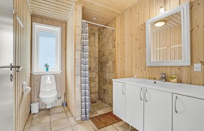 Un baño pequeño con ducha, inodoro y lavamanos.